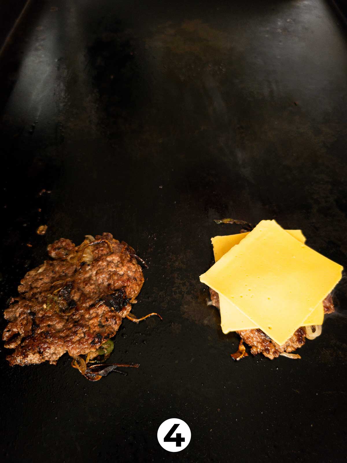 Two slices of american cheese melting on top of burger patties for smash burgers.